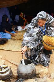 Image du Maroc Professionnelle de  Sous une tente bédouine plusieurs femmes du Sahara  préparent le couscous durant le grand Moussem de Tan Tan, classé en 2005 patrimoine immatériel humain mondial de l'Unesco. Le Moussem est une sorte de foire annuelle, à la fois économique, culturelle et sociale. Chaque année la majorité des tribus et des grandes familles nomades du désert se retrouvent sur un site désertique "Place de la Tolérance et de la Paix " à la périphérie de Tan Tan où  danse, chants, course de chameaux et fantasia font partie des festivités. , Samedi 18 septembre 2004, ((Photo / Abdeljalil Bounhar)